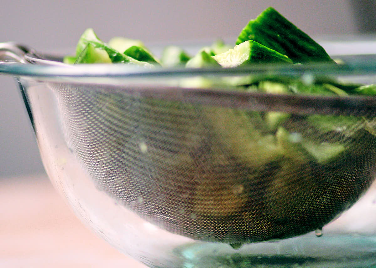 Salted cucumbers in a mesh sieve to drain extra water away.