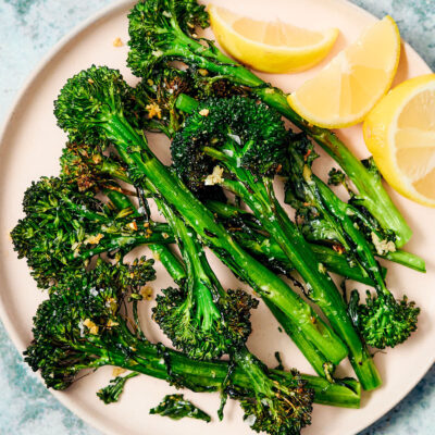 Air Fryer Broccolini on a plate with fresh lemon wedges.