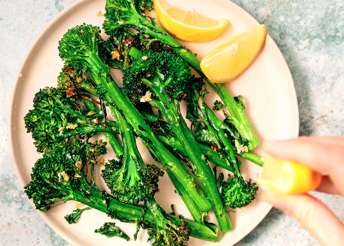 Air fryer broccolini being served with fresh lemon wedges for squeezing.