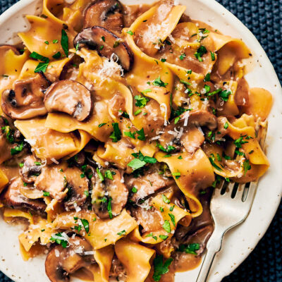 Vegetarian Mushroom Stroganoff on a dinner plate topped with parmesan cheese and parsley.