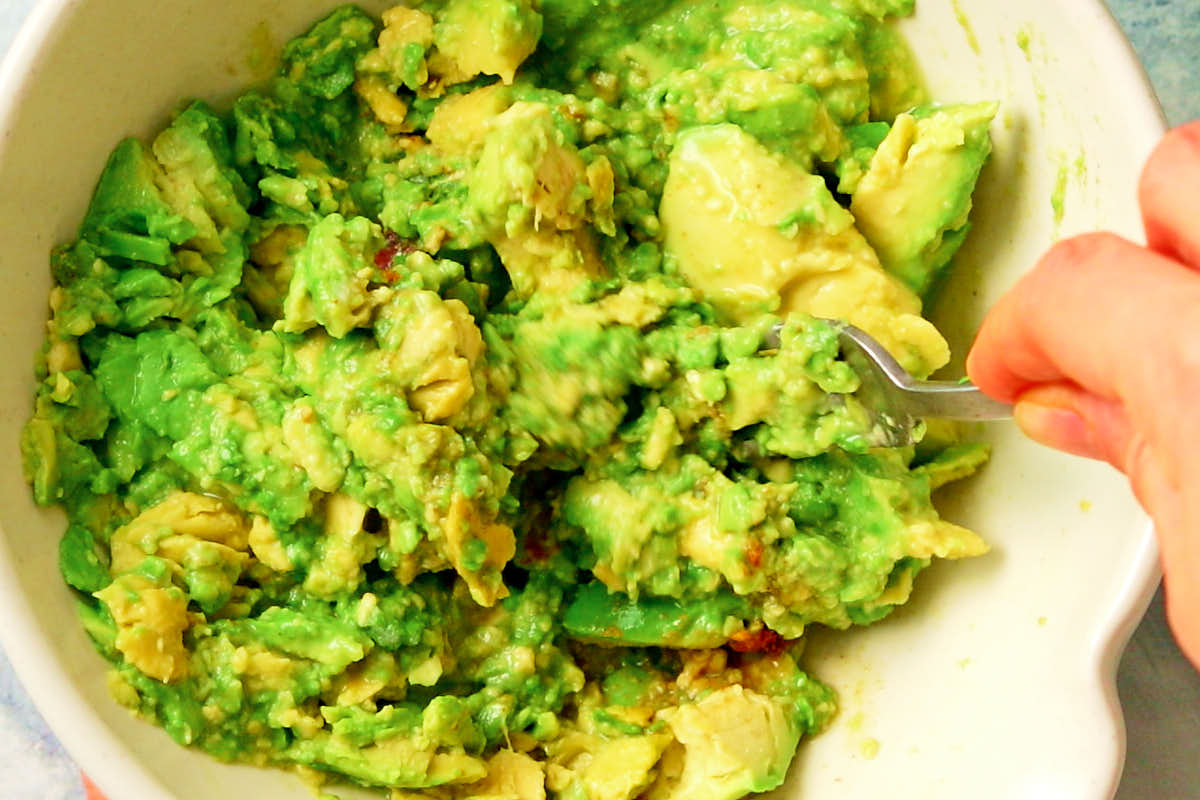 Mashing avocado with a fork to make vegan guacamole.