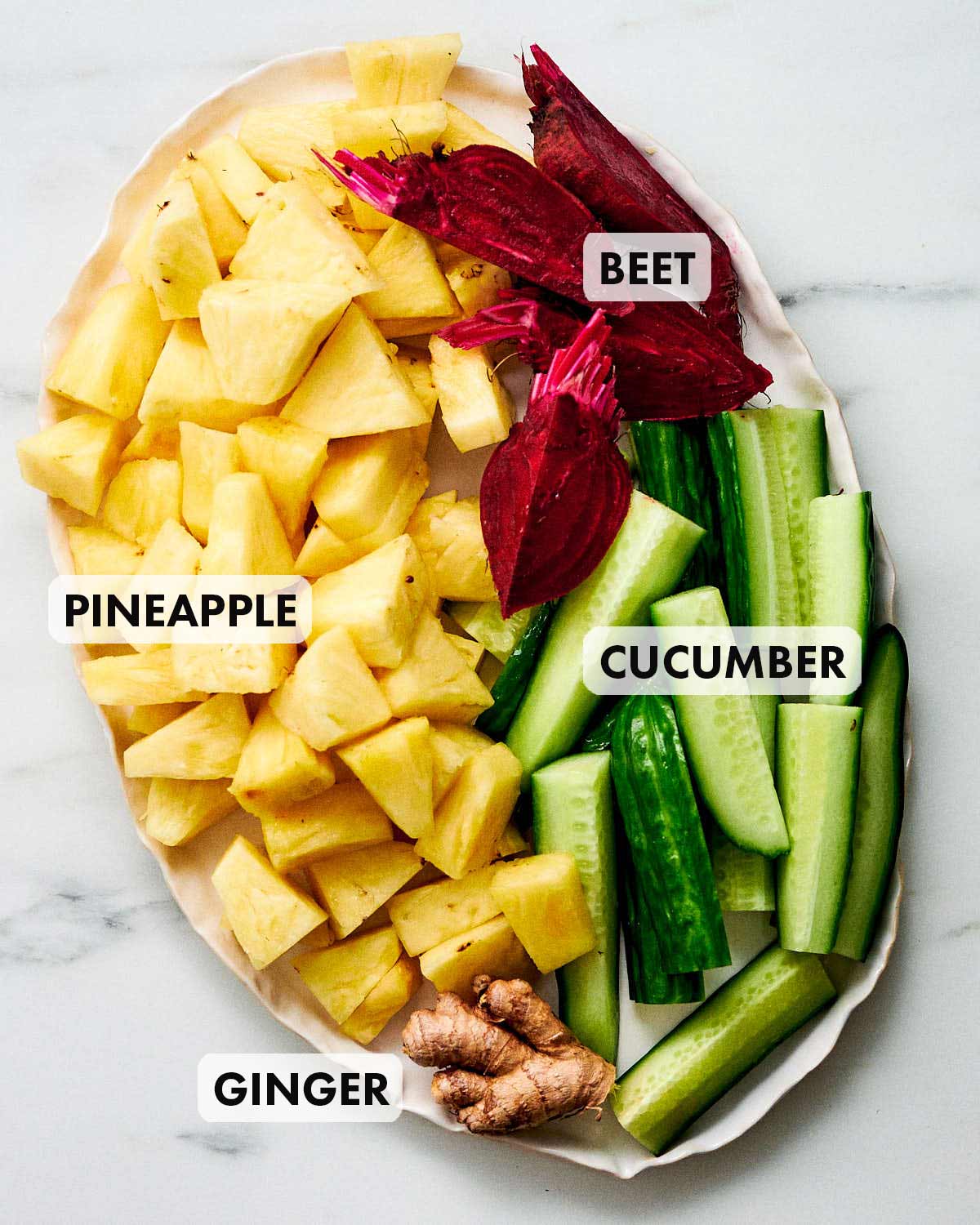 Pineapple, Beet, Cucumber, and Ginger chopped up on a plate.