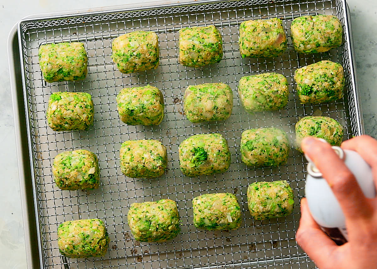 Spraying broccoli tots with oil spray before baking in air fryer.