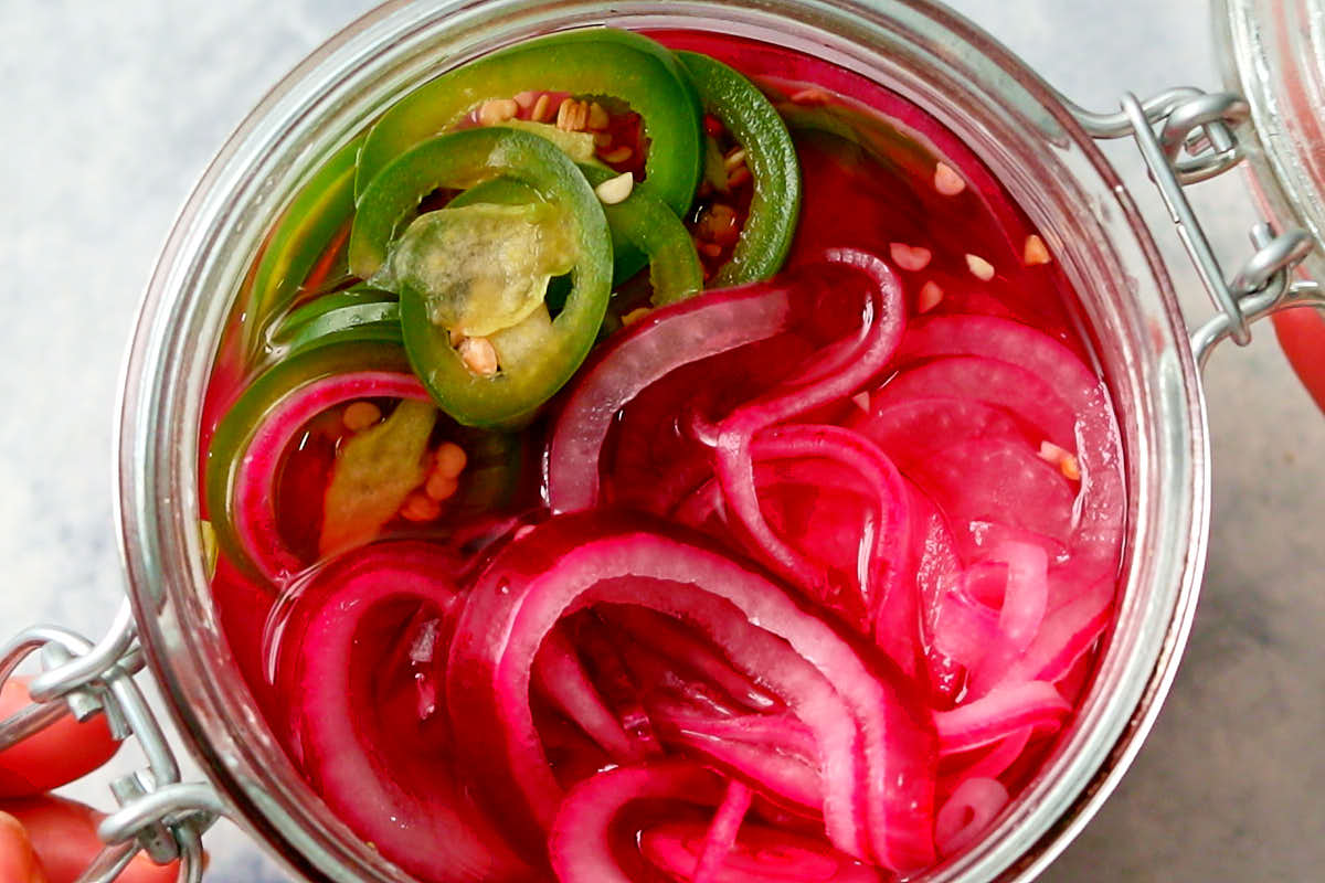 Quick pickled red onions and jalapenos in a glass jar.