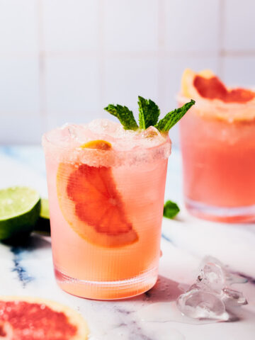 Grapefruit Paloma in a glass with ice, mint, and grapefruit slices.