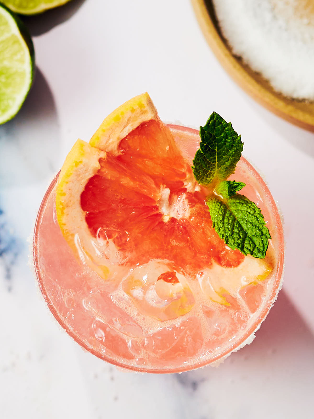 A glass of Grapefruit Paloma Cocktail with a slice of grapefruit and mint.