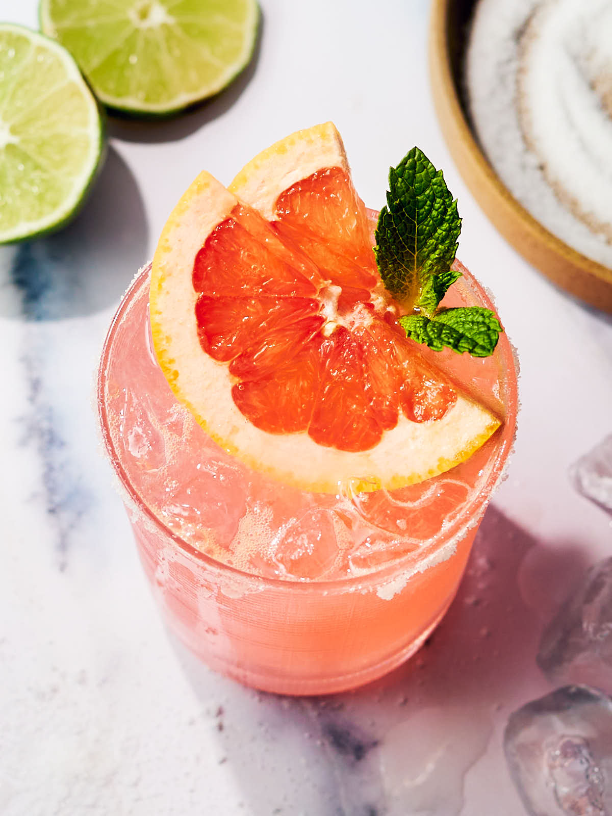 A cocktail glass of Grapefruit Paloma topped with mint.