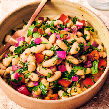 Tuscan bean salad with dill and bell peppers in a bowl.