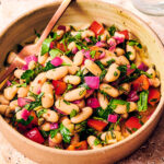 Tuscan bean salad with dill and bell peppers in a bowl.