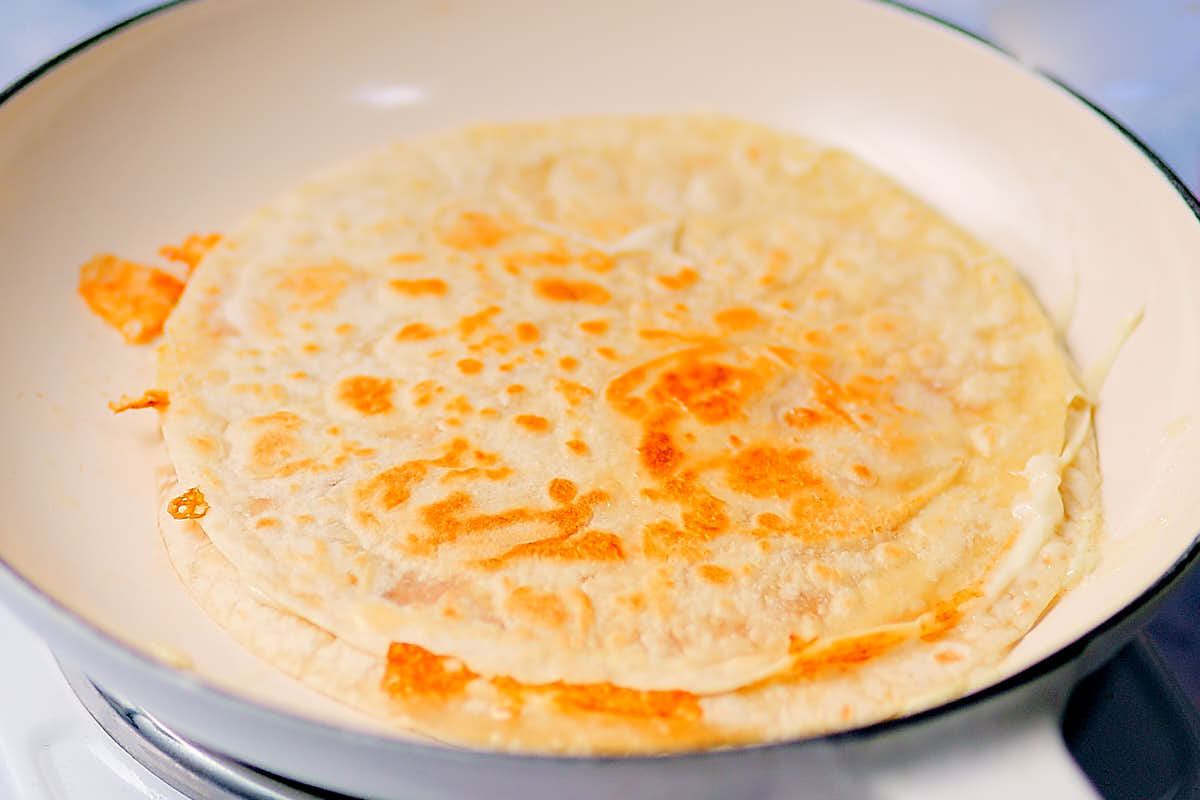 Crispy, golden-brown cheese quesadilla in a skillet.