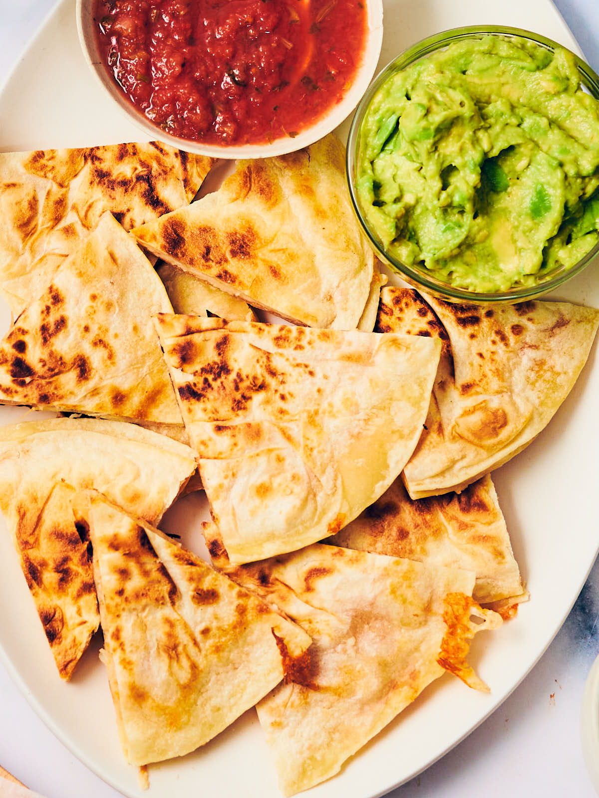 The best cheese quesadillas on a plate with guacamole and salsa.