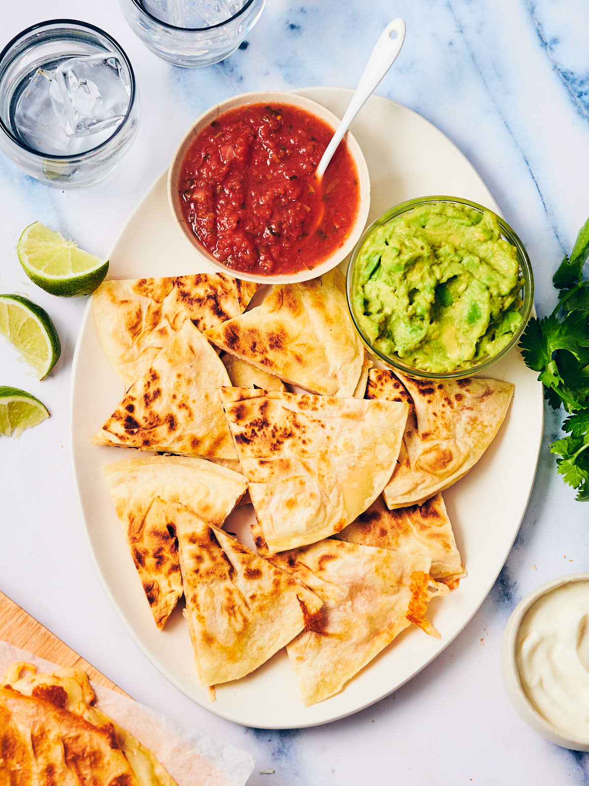 Cheese quesadillas on a plate with guacamole and salsa.