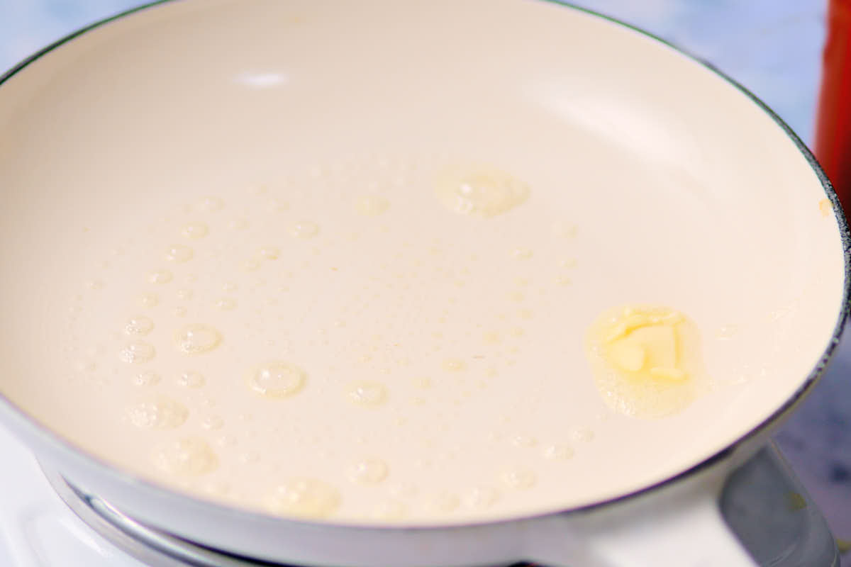 Butter melting in a white skillet pan.
