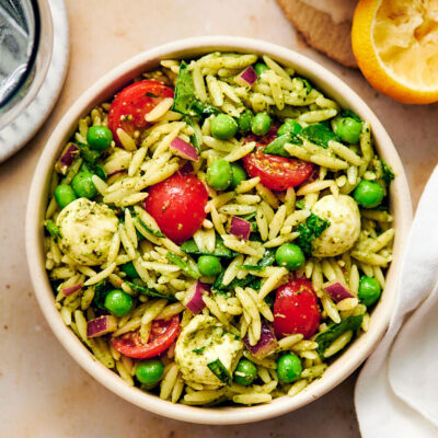 Vegetarian Orzo Pesto Salad with tomatoes, peas, and cheese in a bowl.