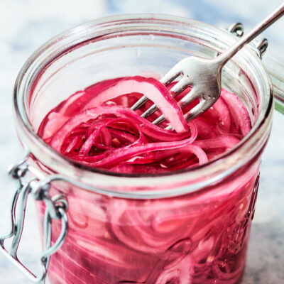 Quick pickled onions in a glass jar with a fork.