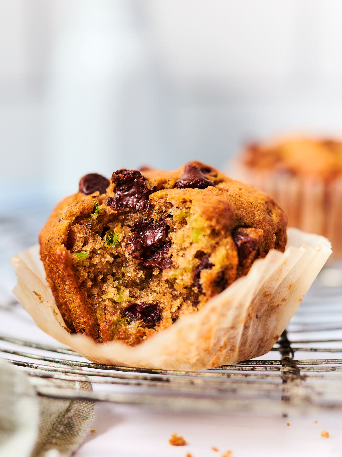 A Vegan Zucchini Muffin with chocolate chips with a bite out of it.