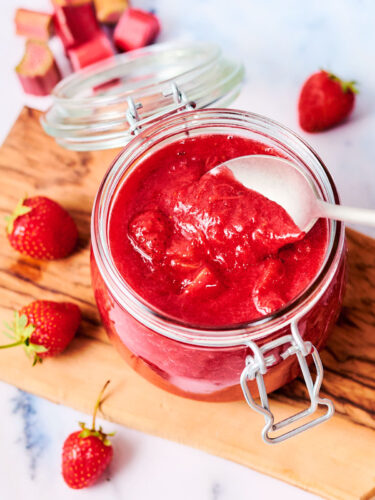 Strawberry Rhubarb Compote in a glass jar with a spoon.