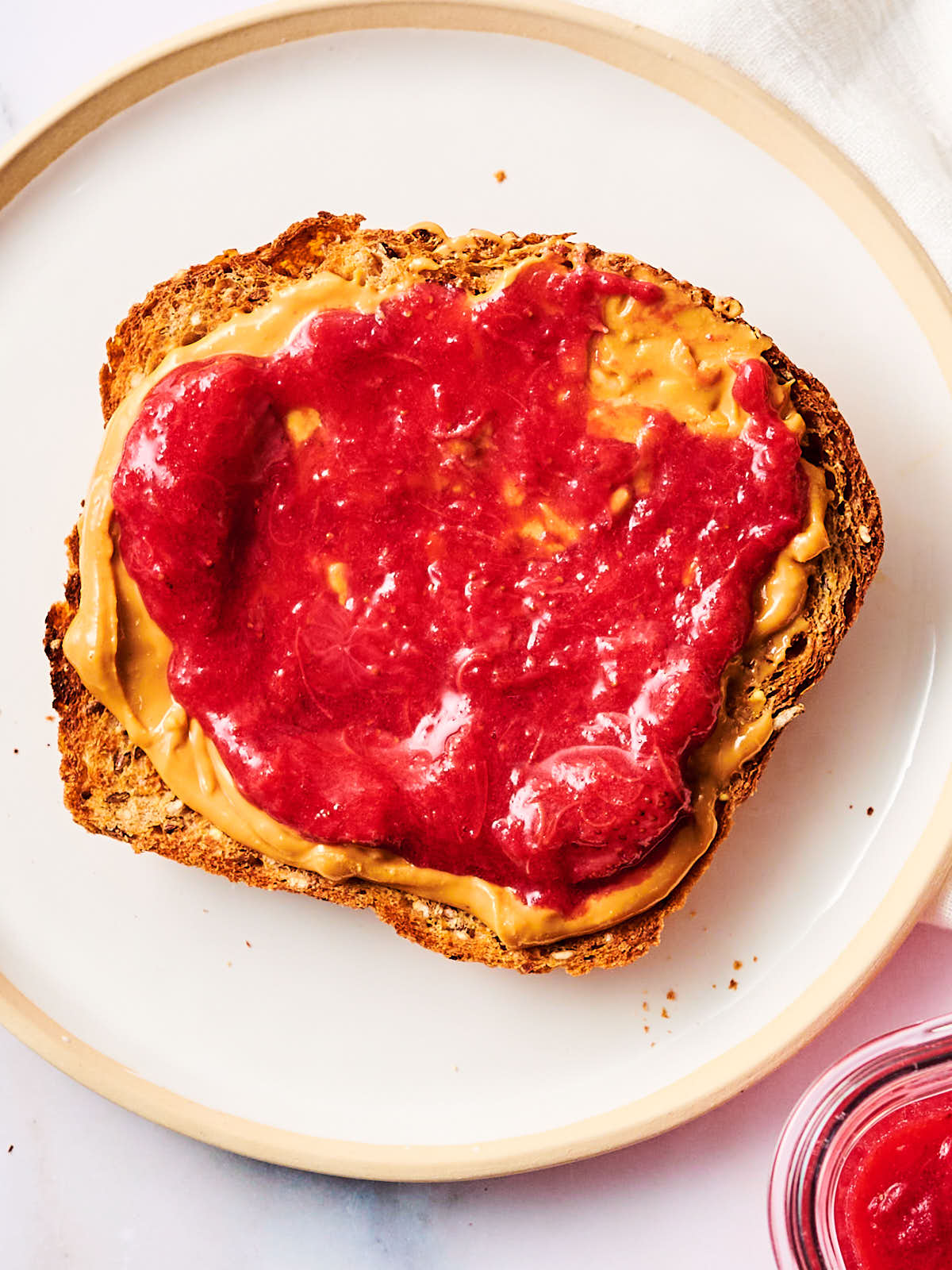 Toast topped with peanut butter and strawberry rhubarb spread.