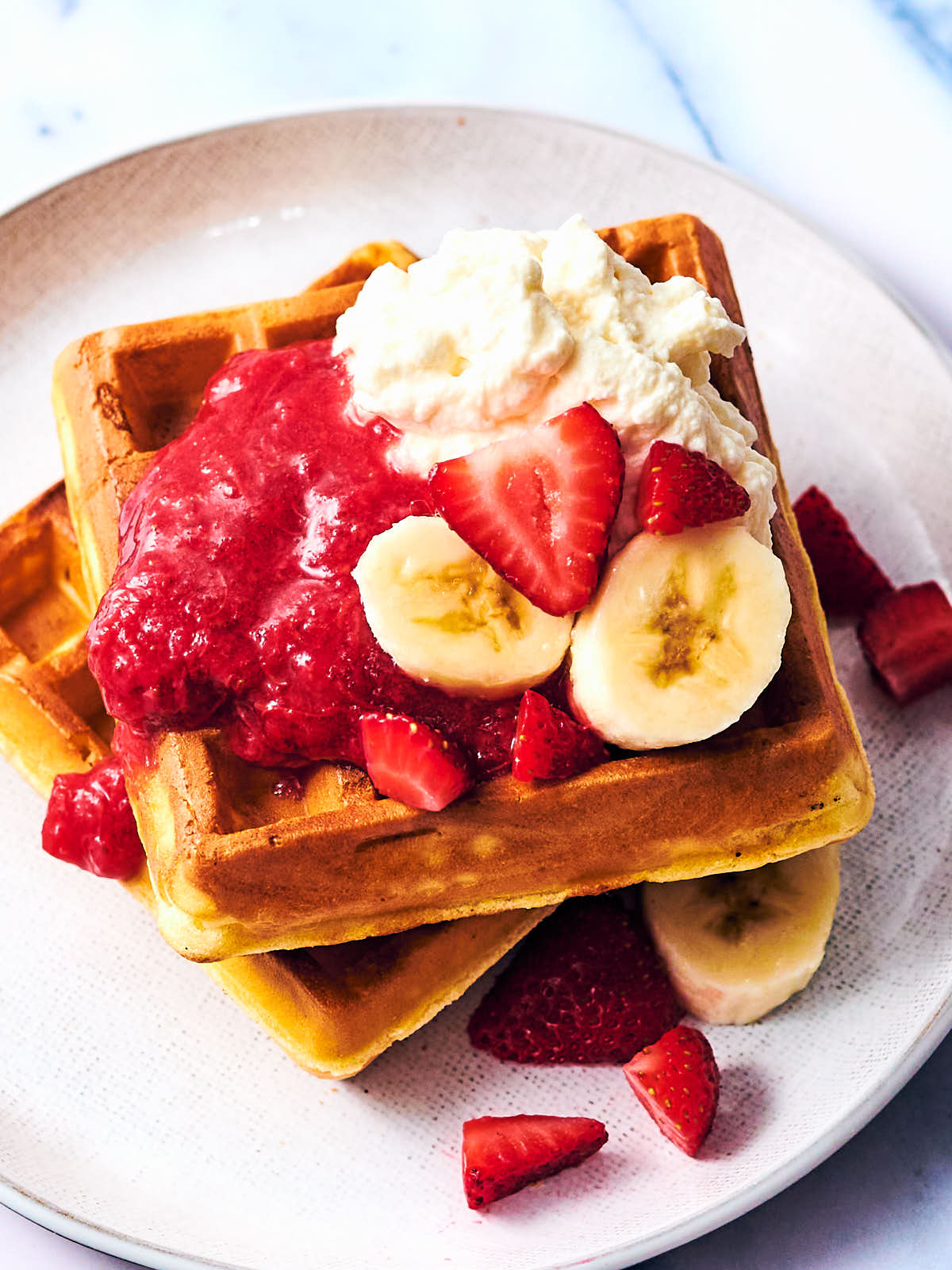 Waffles topped with strawberry rhubarb jam, bananas and whipped cream.