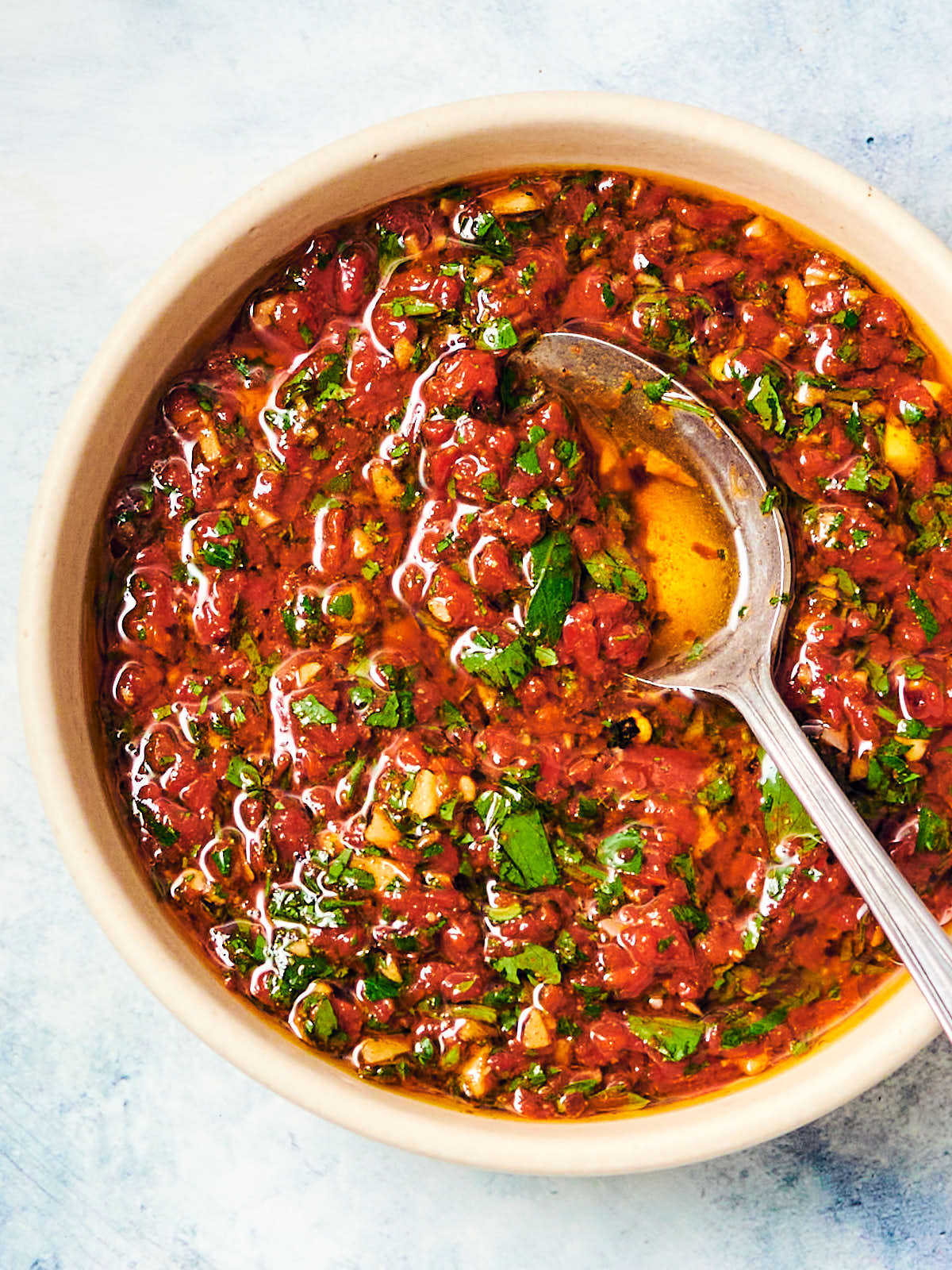 Red Chimichurri (Chimichurri Rojo) in a bowl with a spoon.