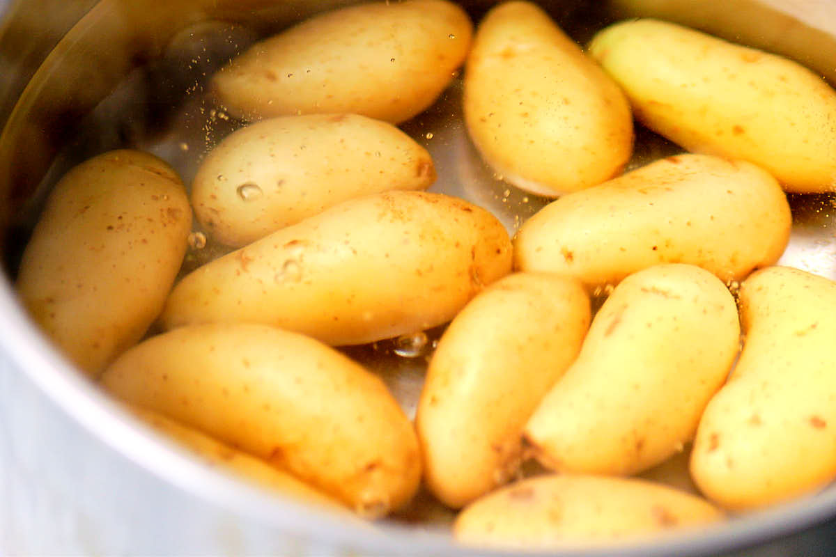 Yellow fingerling potatoes boiling in a pot of water.