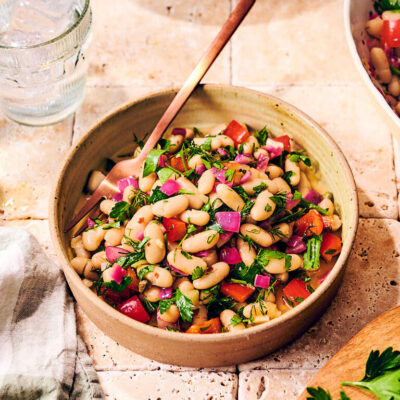 Two bowls of Italian Bean Salad with lemon wedges and parsley.