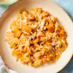 Pumpkin orzo topped with pepper and Parmesan on a plate.