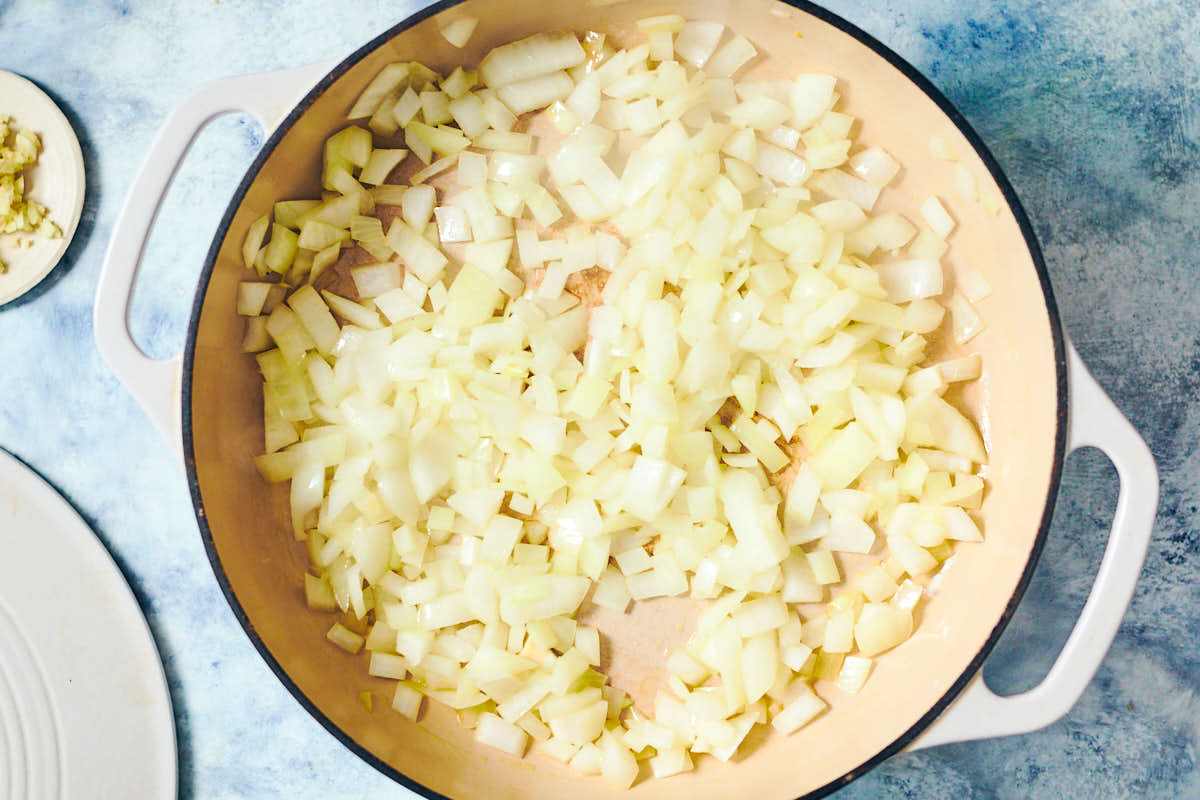 Diced onion being sauteed in a skillet for one pot orzo.