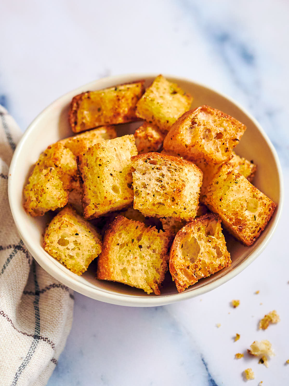 Crispy air fryer croutons in a bowl on a marble counter.