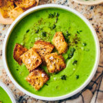 Easy vegan frozen pea soup in a bowl topped with croutons.