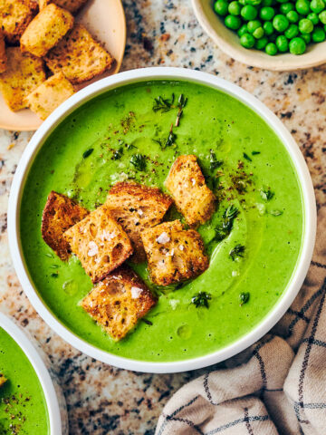 Easy vegan frozen pea soup in a bowl topped with croutons.