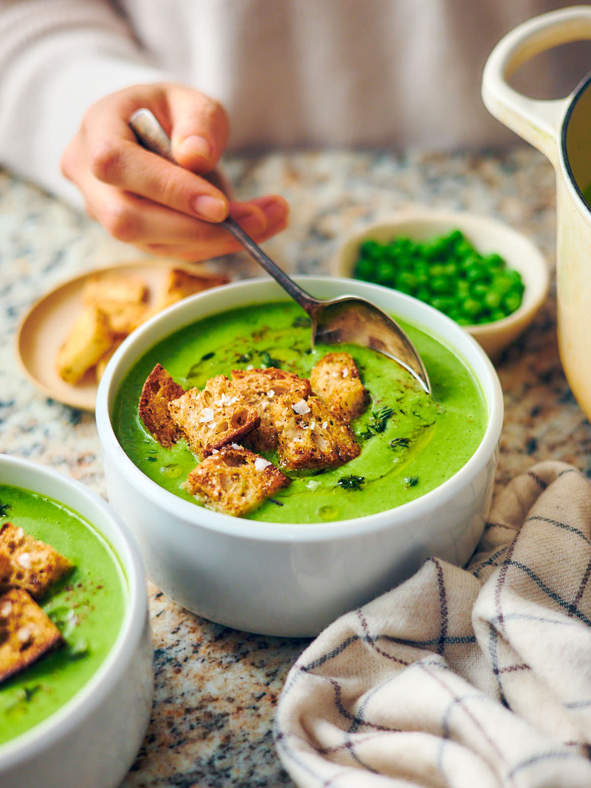 Frozen pea soup in a serving bowl with croutons and a spoon. 