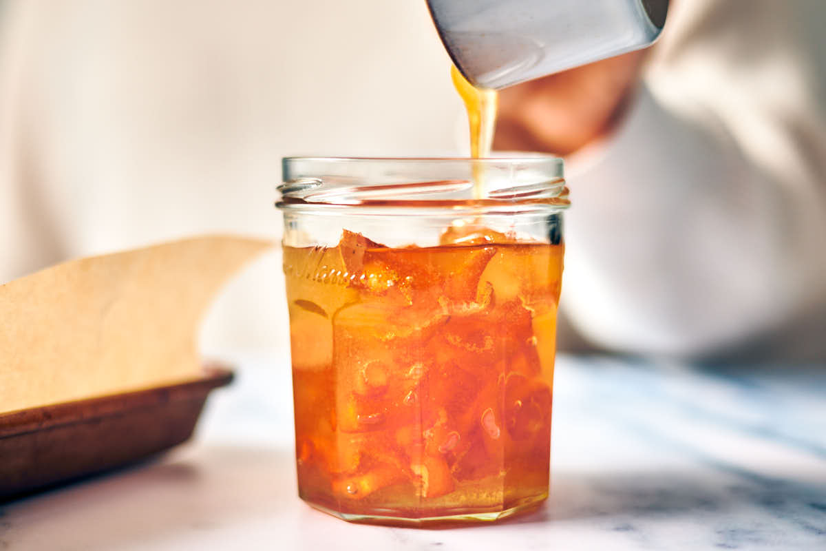 Honey and dried orange rind in a glass jar for infused orange honey.