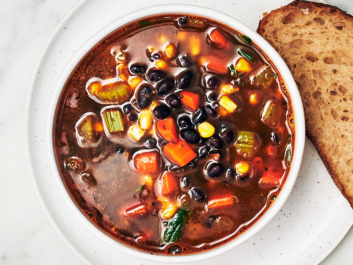 Black bean and vegetable soup in a bowl with bread.