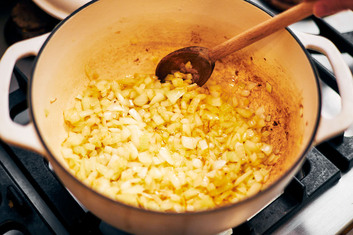 Sauteing diced onion in a pot with a wooden spoon.