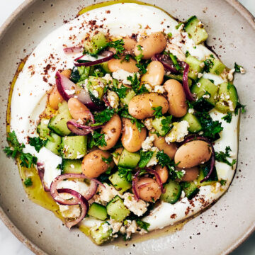 Vegetarian butter bean salad with feta on a plate with yogurt and sumac.