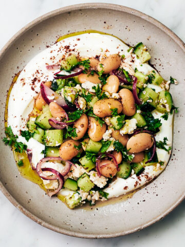 Vegetarian butter bean salad with feta on a plate with yogurt and sumac.