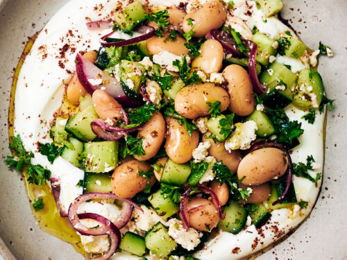 Vegetarian butter bean salad with feta on a plate with yogurt and sumac.