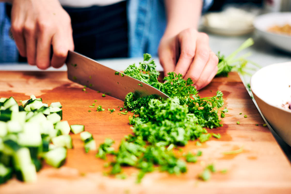 Parsley being chopped on a cutting board for butter bean salad.