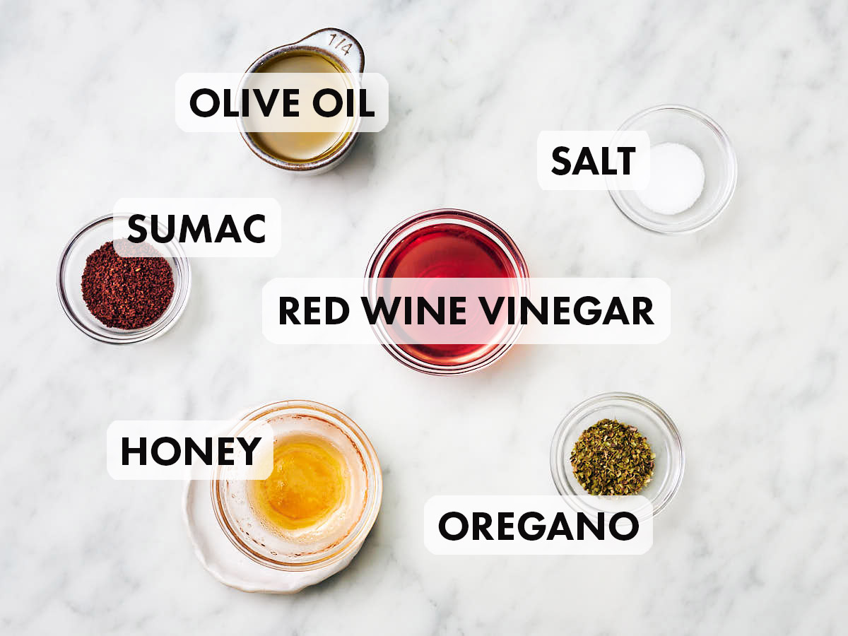 Ingredients to make Sumac dressing (olive oil, red wine vinegar, sumac, oregano, salt, honey).