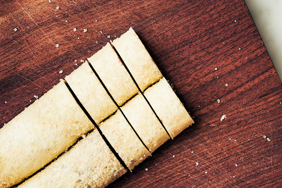 Slicing log of puff pastry dough to make palmier cookies.