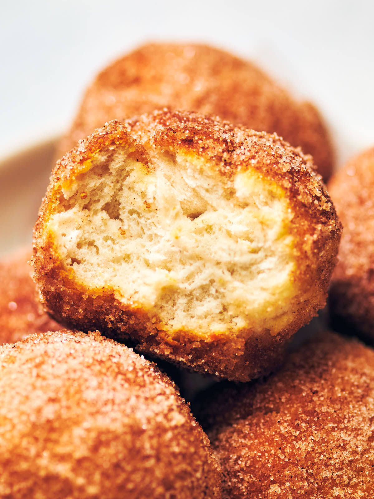 A cinnamon sugar air fryer donut hole with a bite taken out of it.