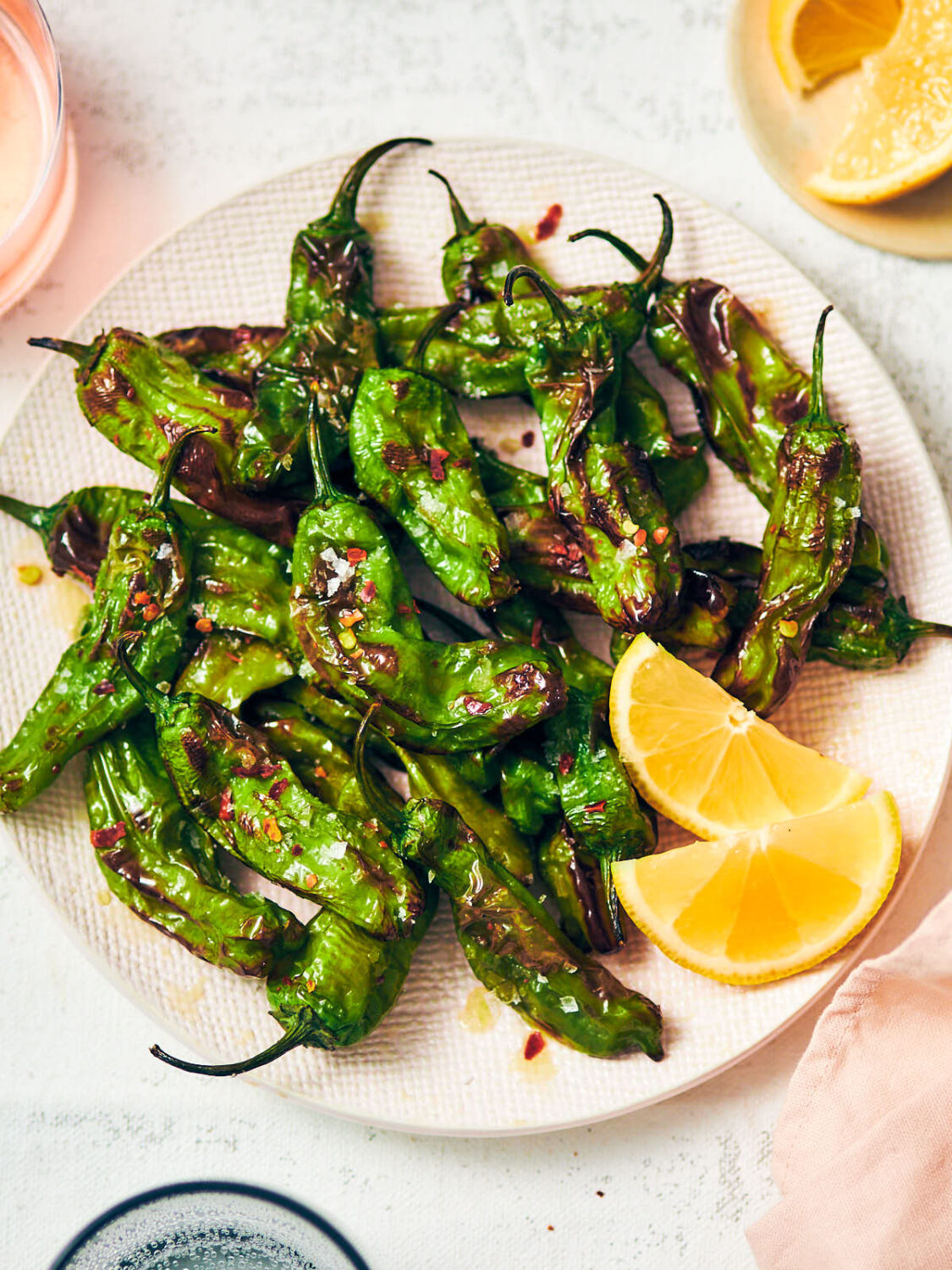 Air Fryer Shishito Peppers with lemon and sesame oil on a plate.