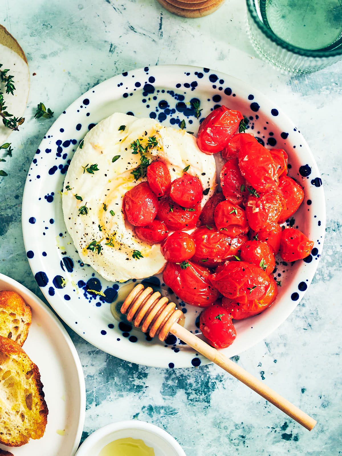 The best air fryer tomatoes on a plate with whipped ricotta dip, honey, and fresh thyme.
