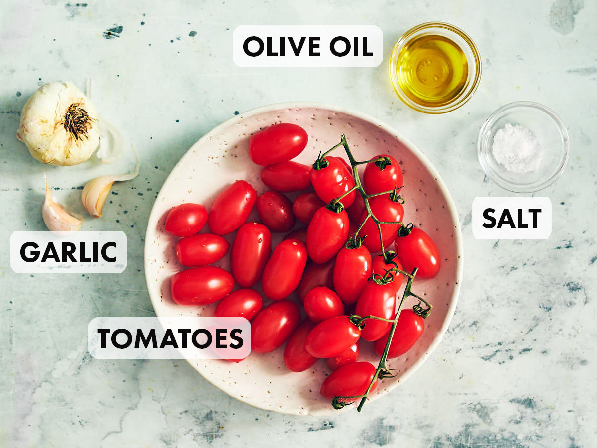 Ingredients to make air fryer tomatoes: cherry tomatoes, garlic, olive oil, and salt in bowls.
