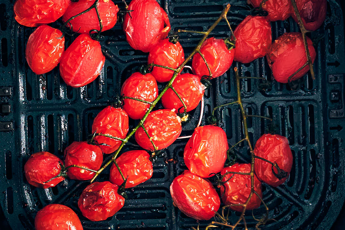 Cherry tomatoes roasted on the vine in an air fryer basket.