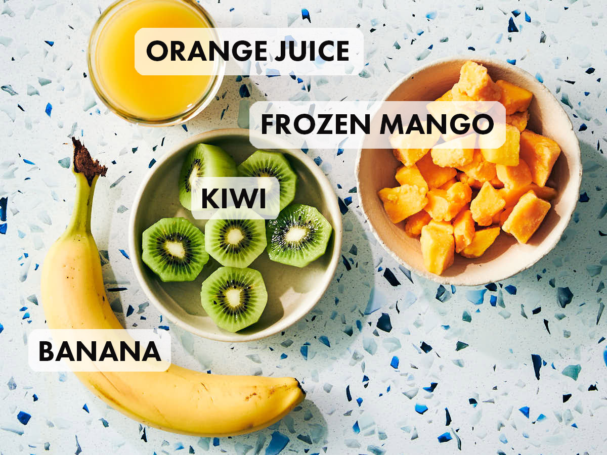 Mango, kiwi, banana and orange juice on a kitchen counter. 