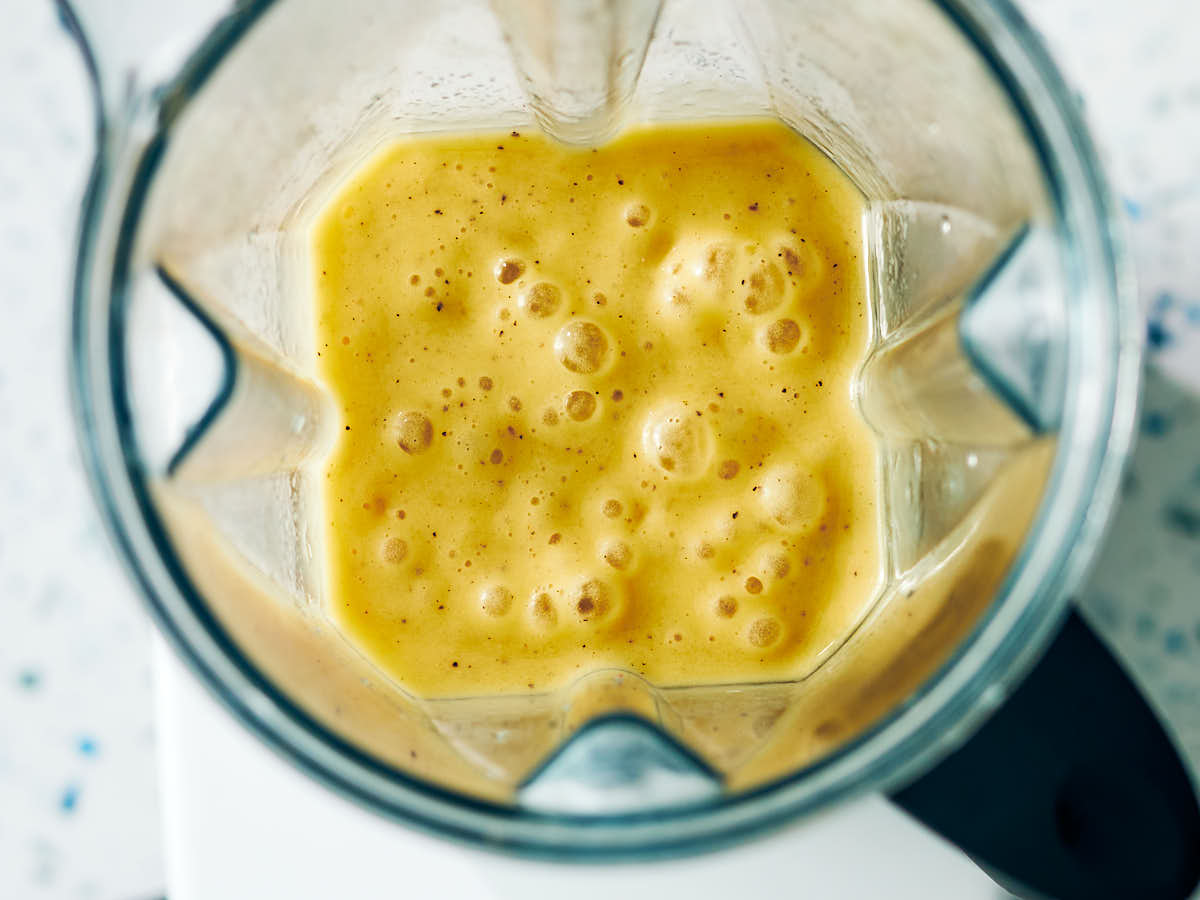 Creamy mango kiwi smoothie in a blender after being blended.