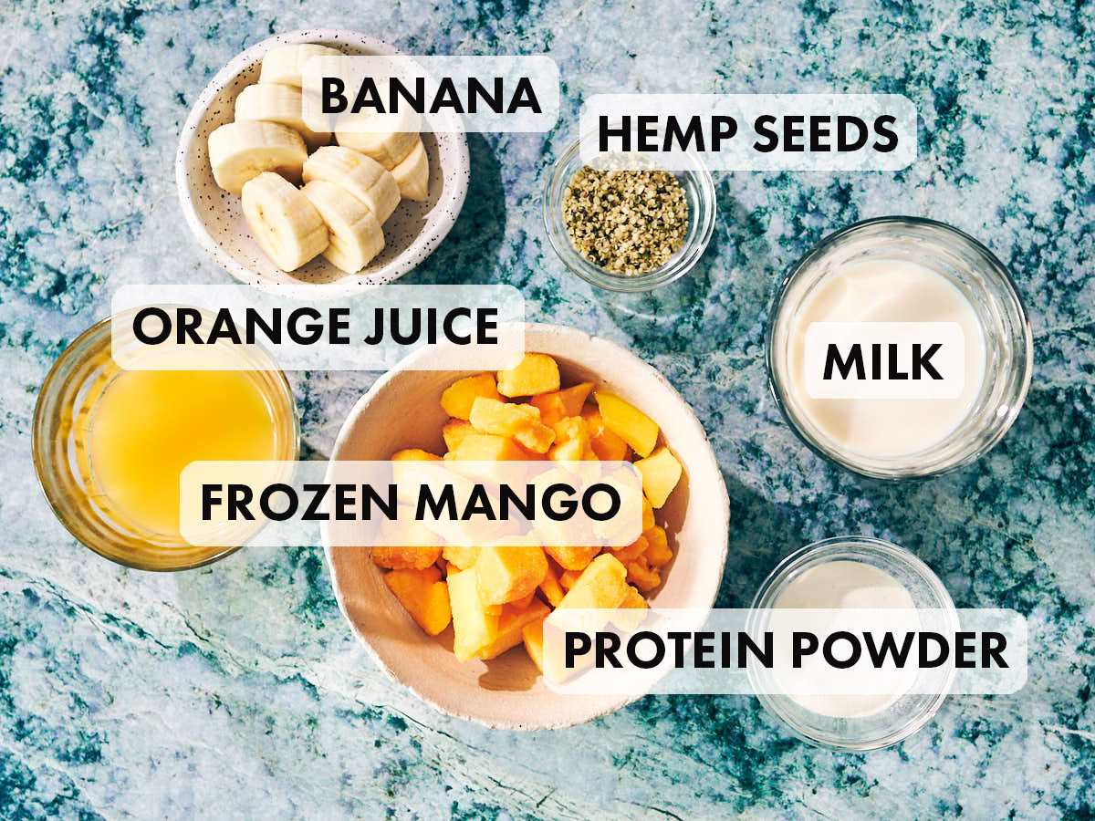 Ingredients to make a vegan mango protein smoothie, including orange juice, milk, and banana.