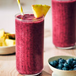 Pineapple Blueberry Smoothies in glasses with a pineapple garnish.